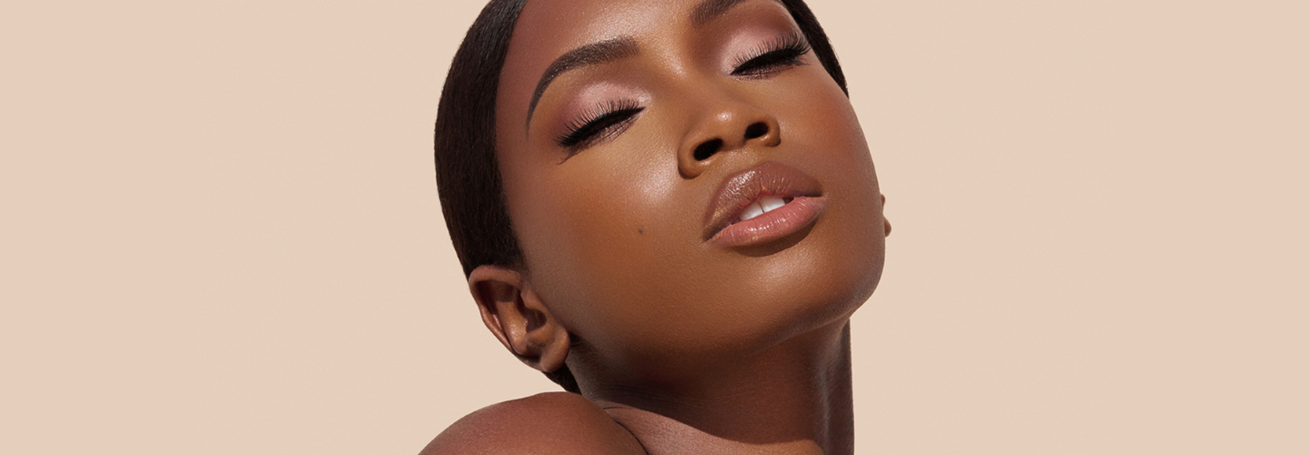 Close-up portrait of a person with eyes closed, head tilted back slightly, against a neutral beige background.