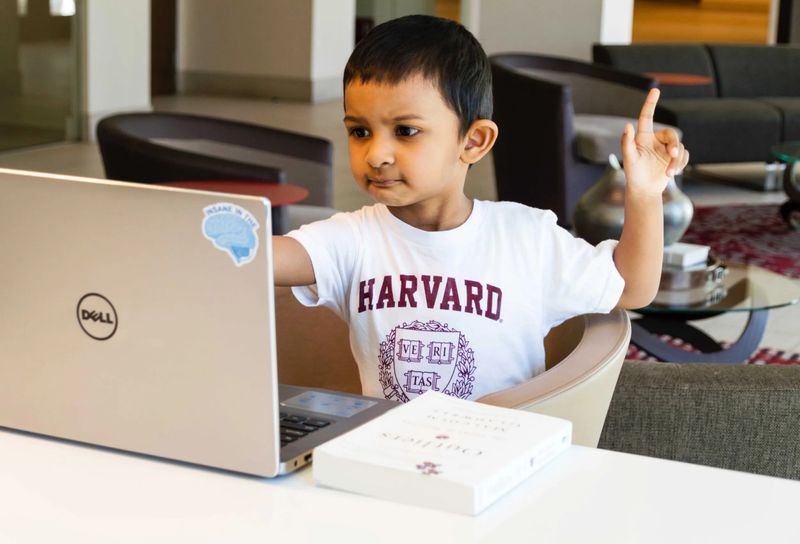 boy at laptop wearing Harvard t-shirt 