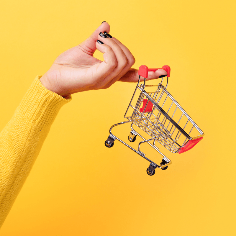 small shopping cart dangling from the tip of a finger