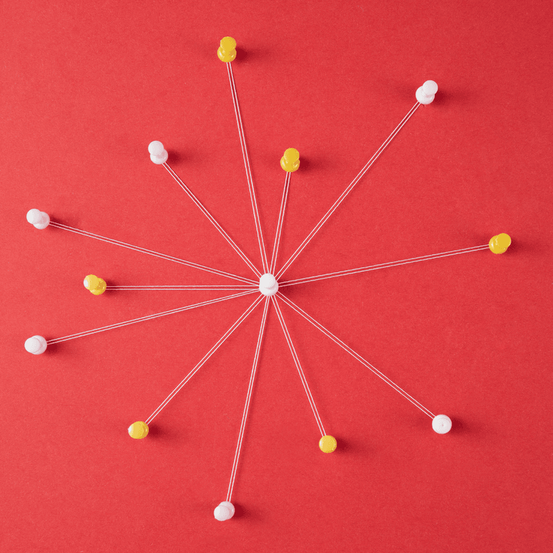 thumbtacks and thread connected on a red background