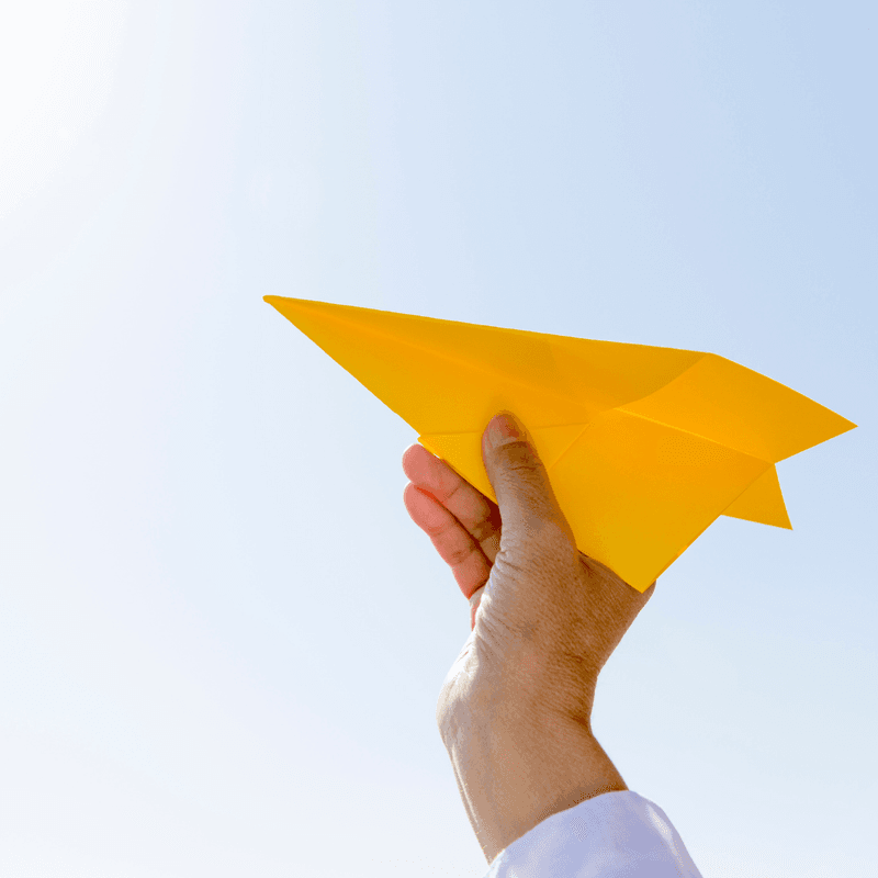 yellow paper airplane pointed upward 