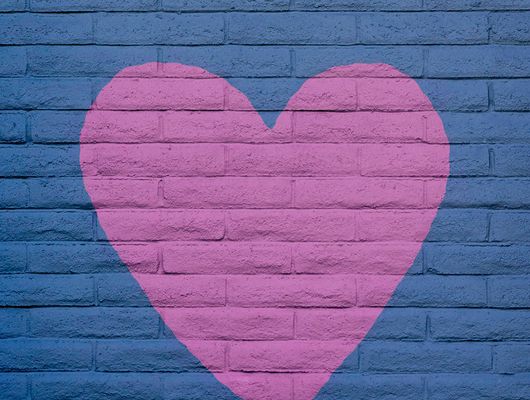 A pink heart painted over a purple brick wall outside representing the article "The Truth About Whether to Make Your Nonprofit Drupal Website Headless"