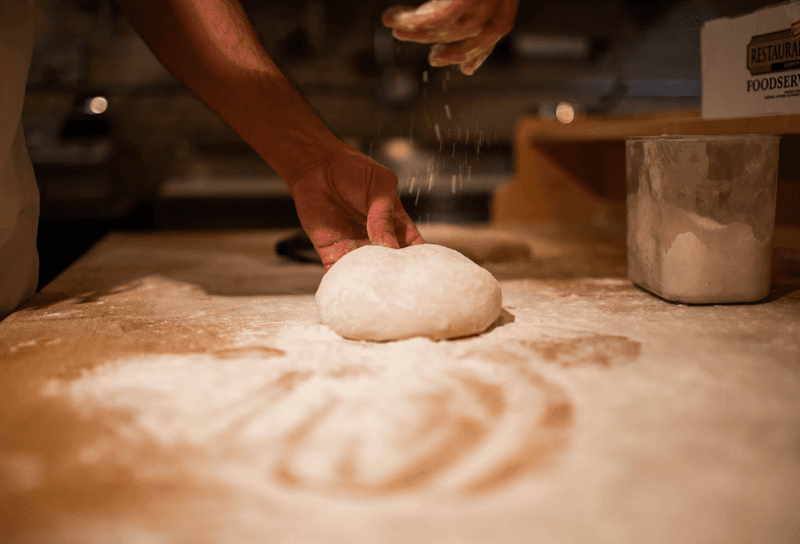 A person sprinkling flour on dough