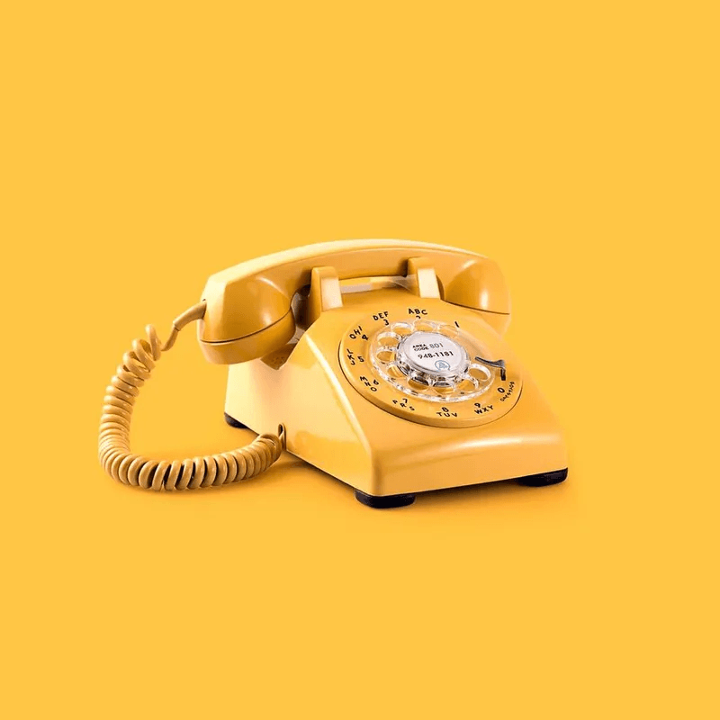 yellow rotary phone on a yellow background 
