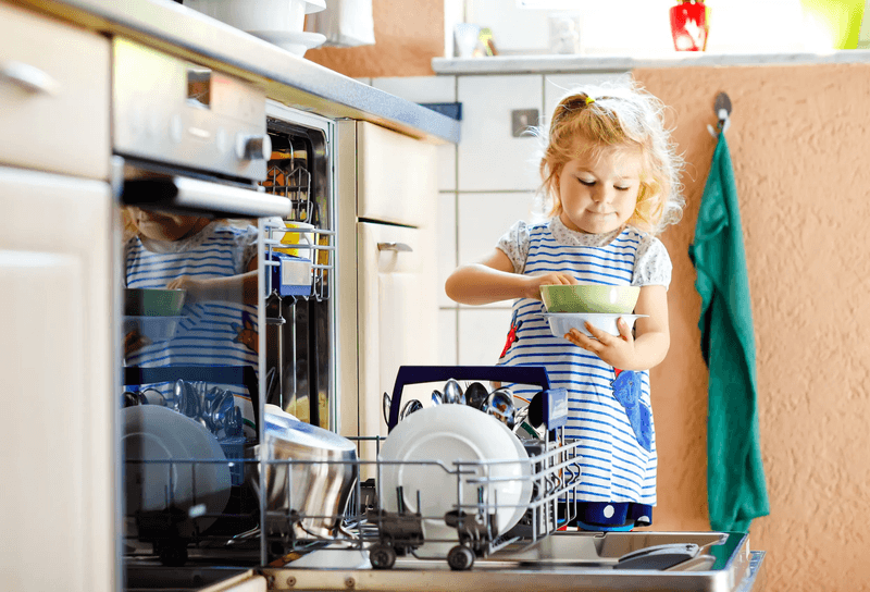 Child standing in kitchen next to dishwasher