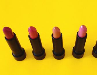 Pink lipsticks lined up on yellow background.